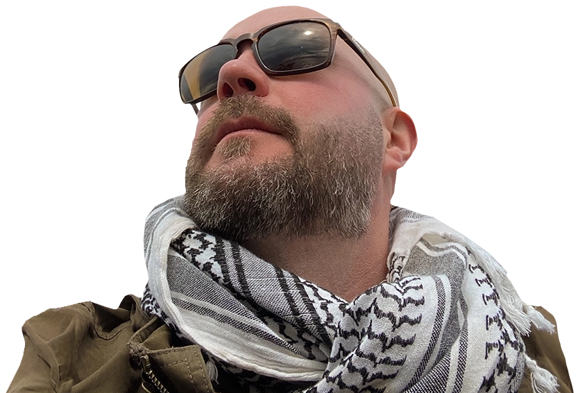 Photo of a man with a beard wearing sunglasses and a brown jacket.