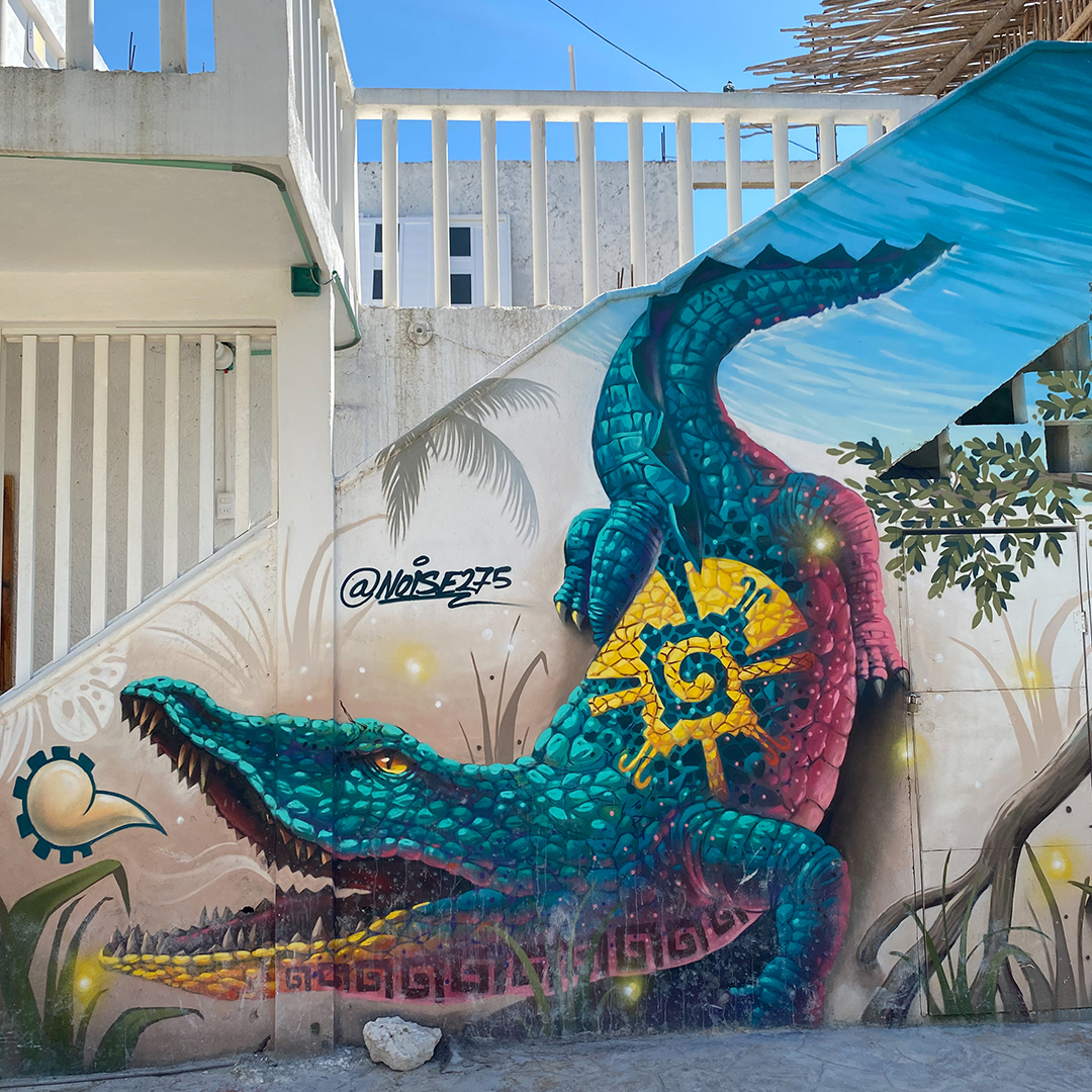 Graffiti of a colourful blue and yellow crocodile on a wall.